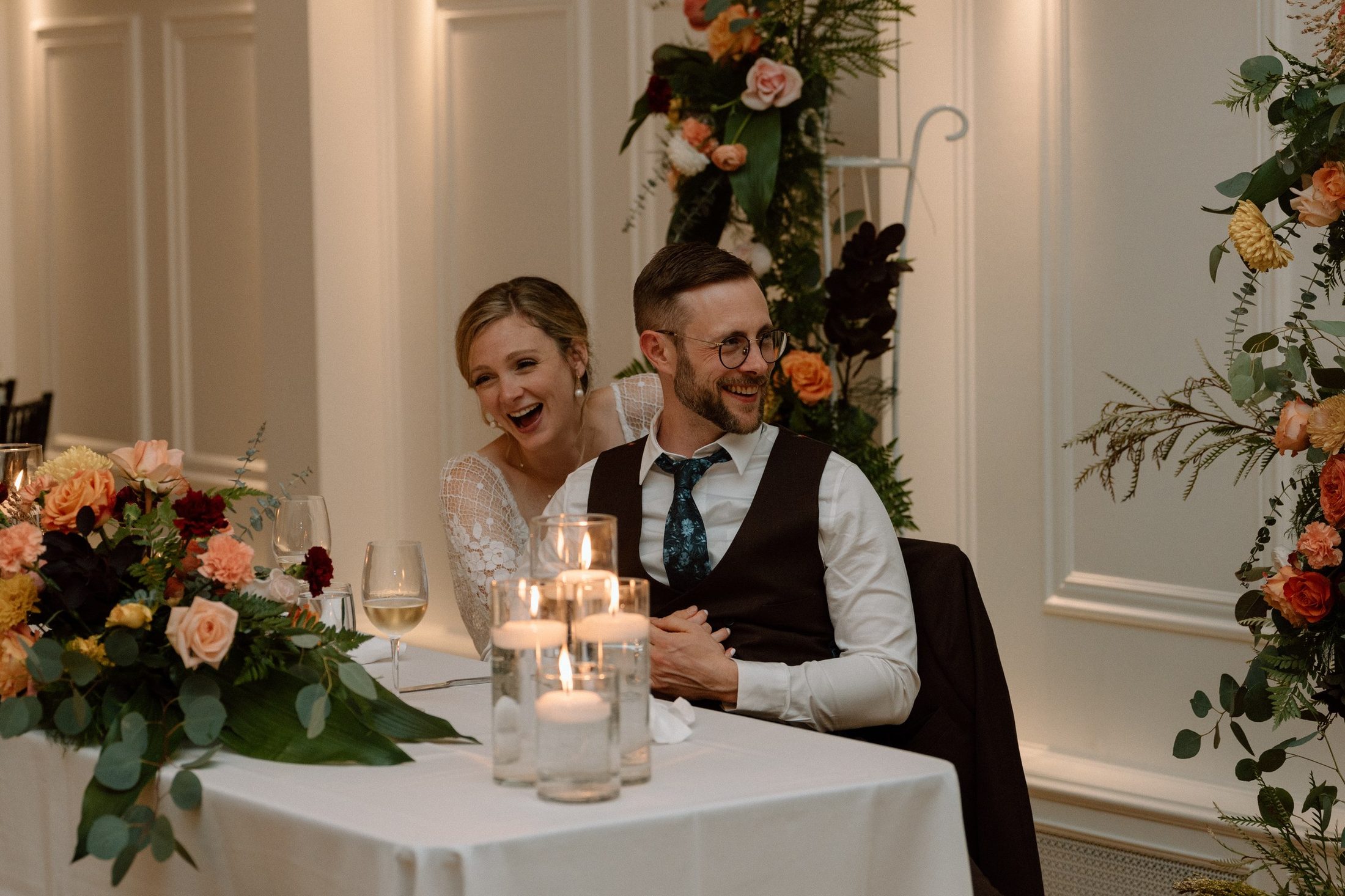 The couple laughing together at the sweetheart table