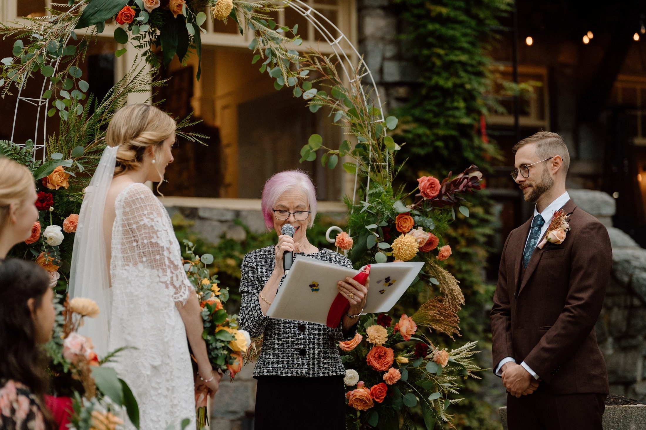 An emotional moment during the vows, framed by a floral arch